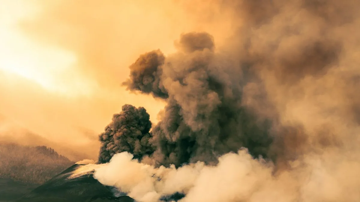 火口から灰色の噴煙が斜面を覆うように噴き上がっている火山