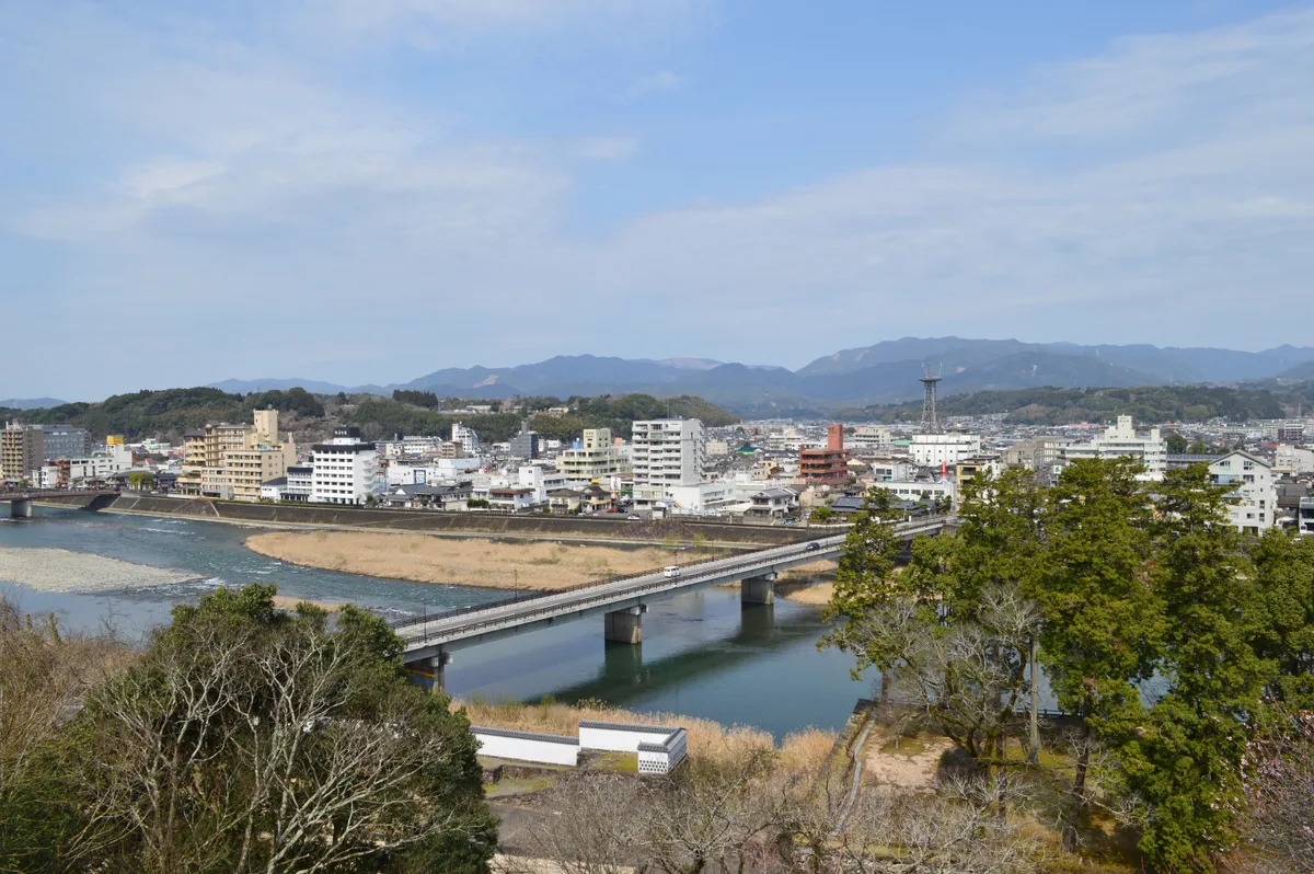 人吉城跡から見下ろした人吉市街。手前に球磨川と橋があり、その向こうに市街地、奥に山が連なる