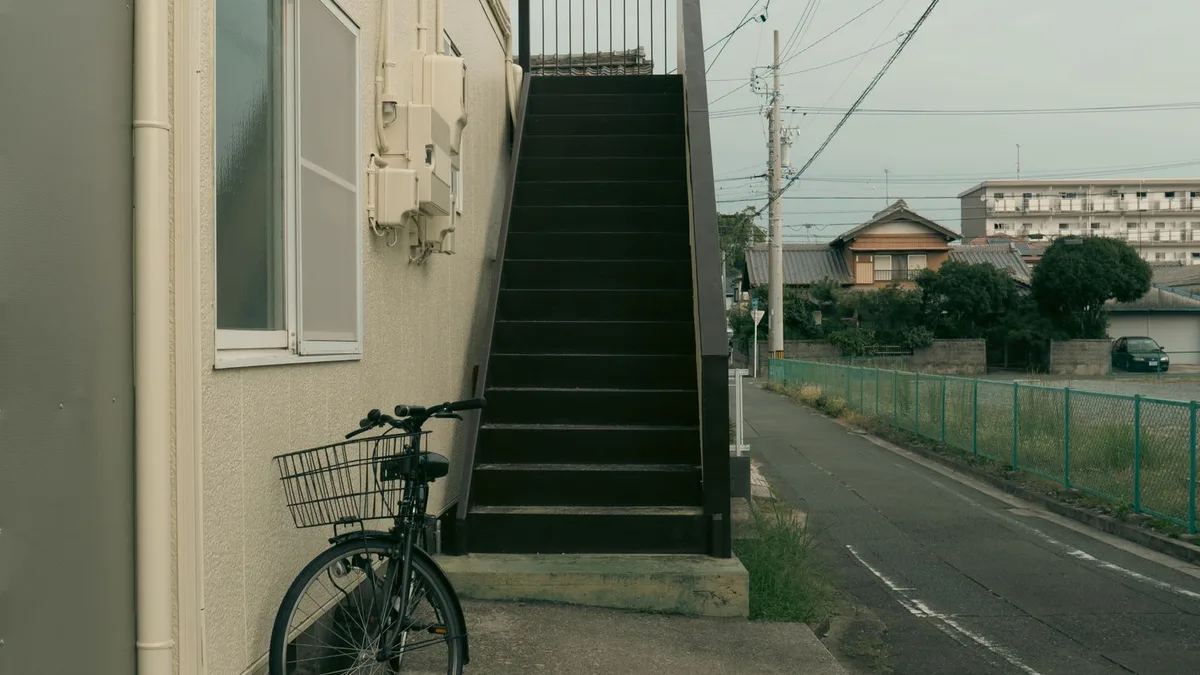 道路とほぼ同じ高さに玄関がある日本のアパートの1階。外階段と自転車が見える