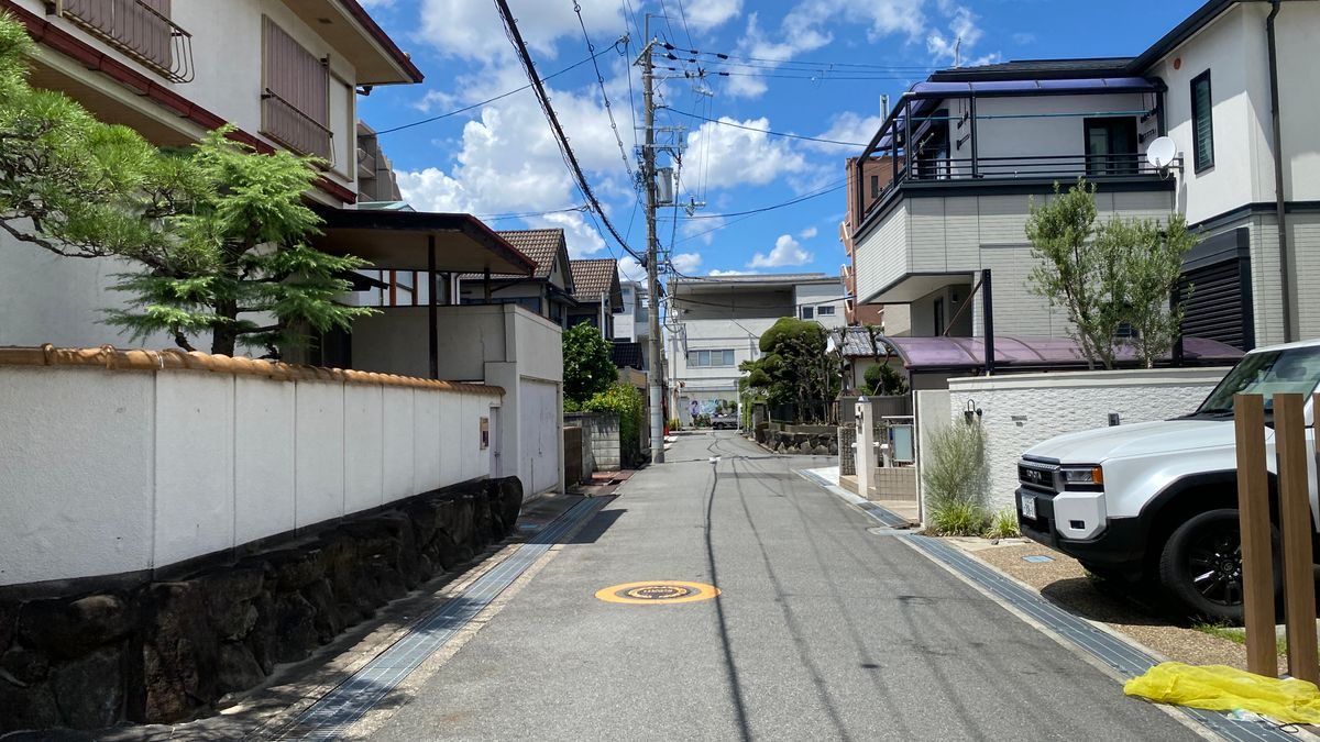 古い和風の家と新しい住宅が並ぶ、晴れた日の住宅街の細い道