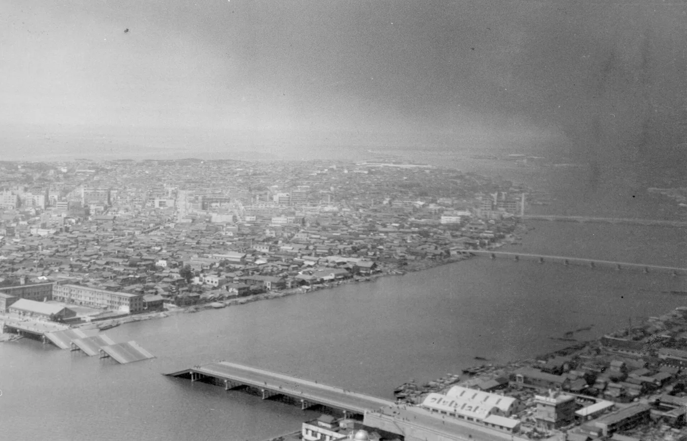 1964年新潟地震の翌日に上空から撮影した新潟市街と信濃川。手前の橋の桁が川に落ちている