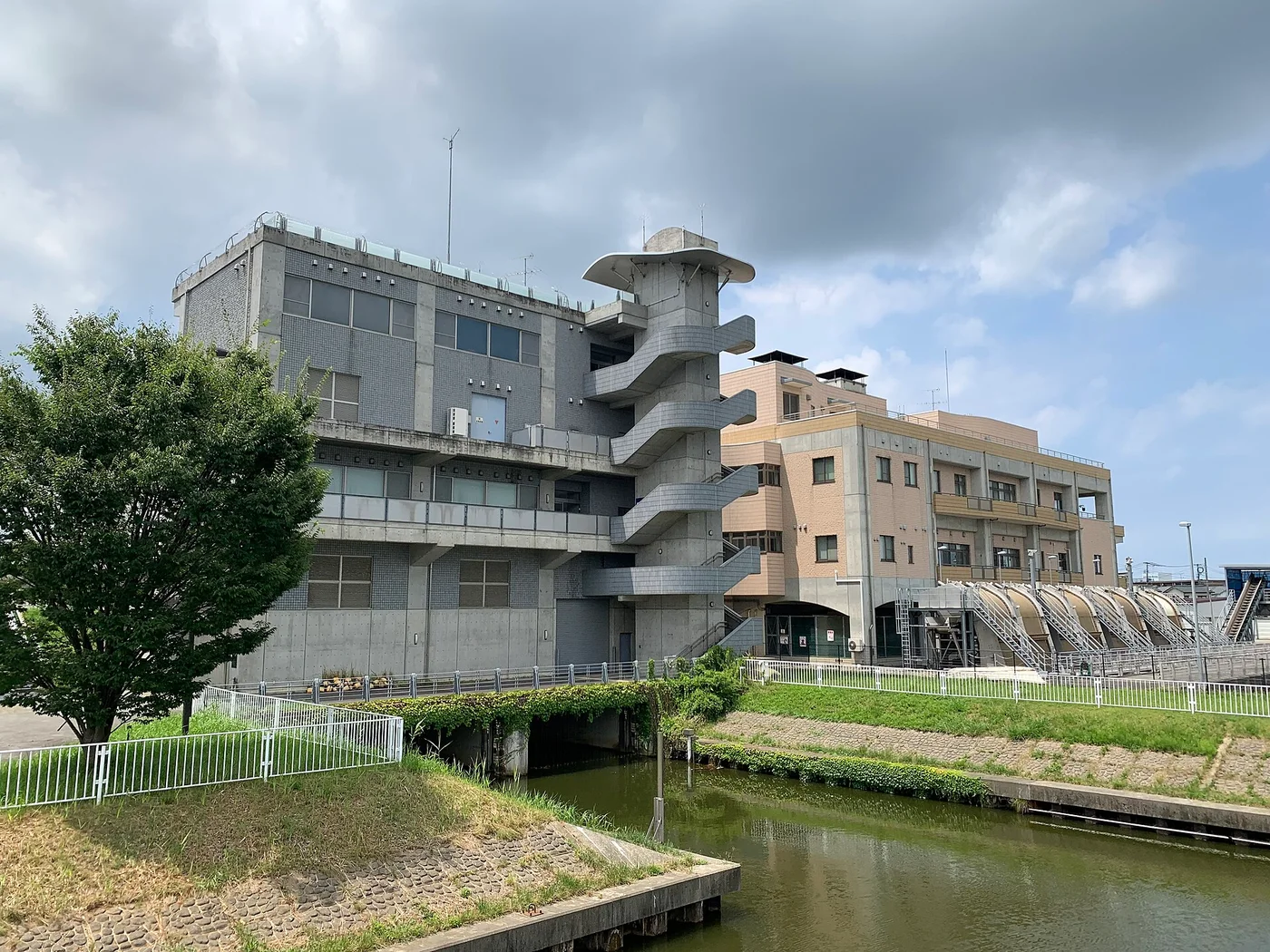 鳥屋野潟のそばに建つ排水機場。コンクリートの建物と、水路に向かって並ぶ排水管