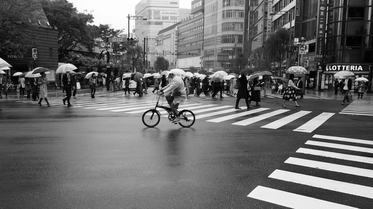 雨の交差点を傘をさして渡る人たちのモノクロ写真