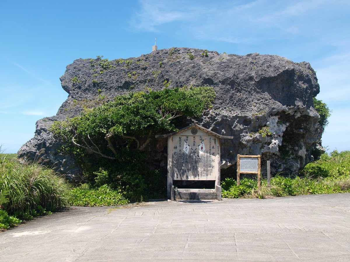 宮古列島下地島の帯岩。海食崖の上に載った巨大な岩塊で、手前に案内板と舗装路がある