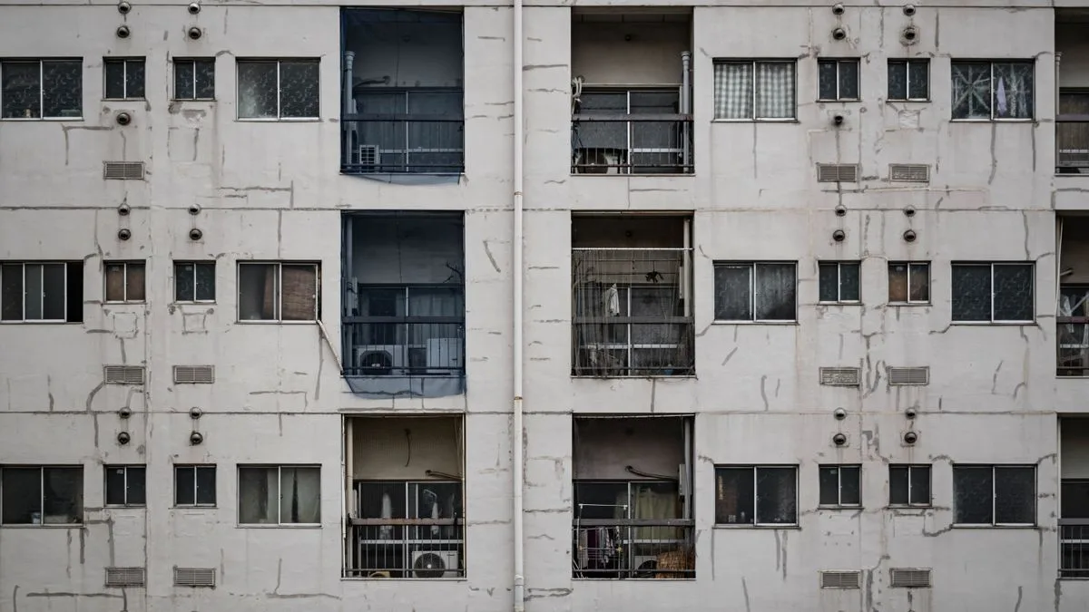 外壁が古びた集合住宅の正面。同じ形の窓とベランダが並んでいる