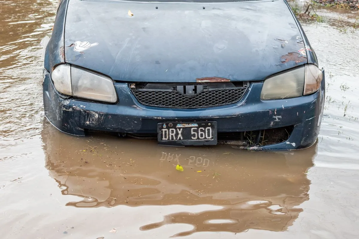 ナンバープレートのすぐ下まで泥水に浸かった青い乗用車