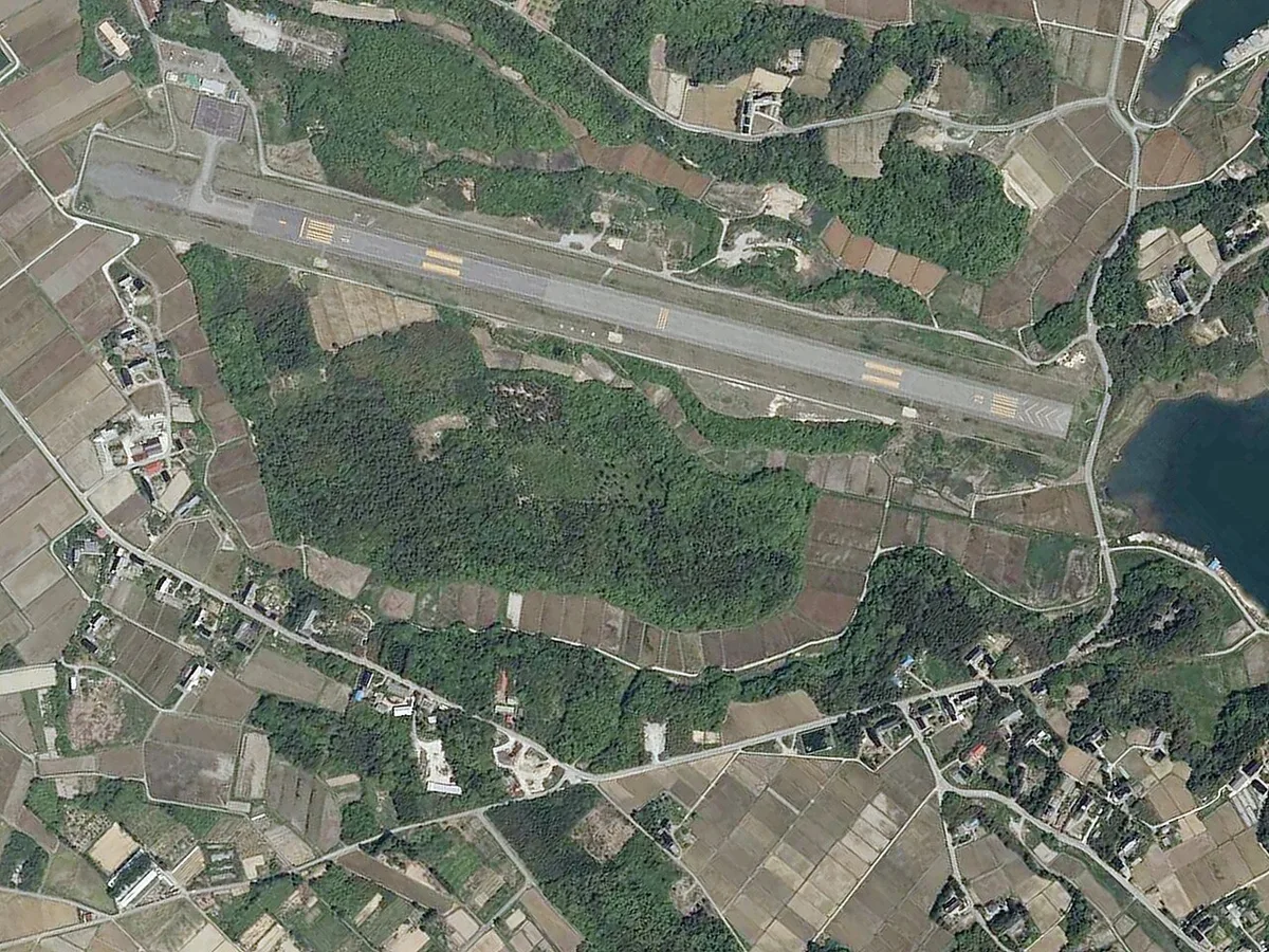 佐渡空港と国仲平野の空中写真。平野の住宅地と農地、その周囲の山地が見える