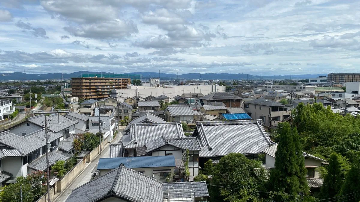 高い位置から見た住宅地。戸建ての屋根が並び、遠くに山が見える
