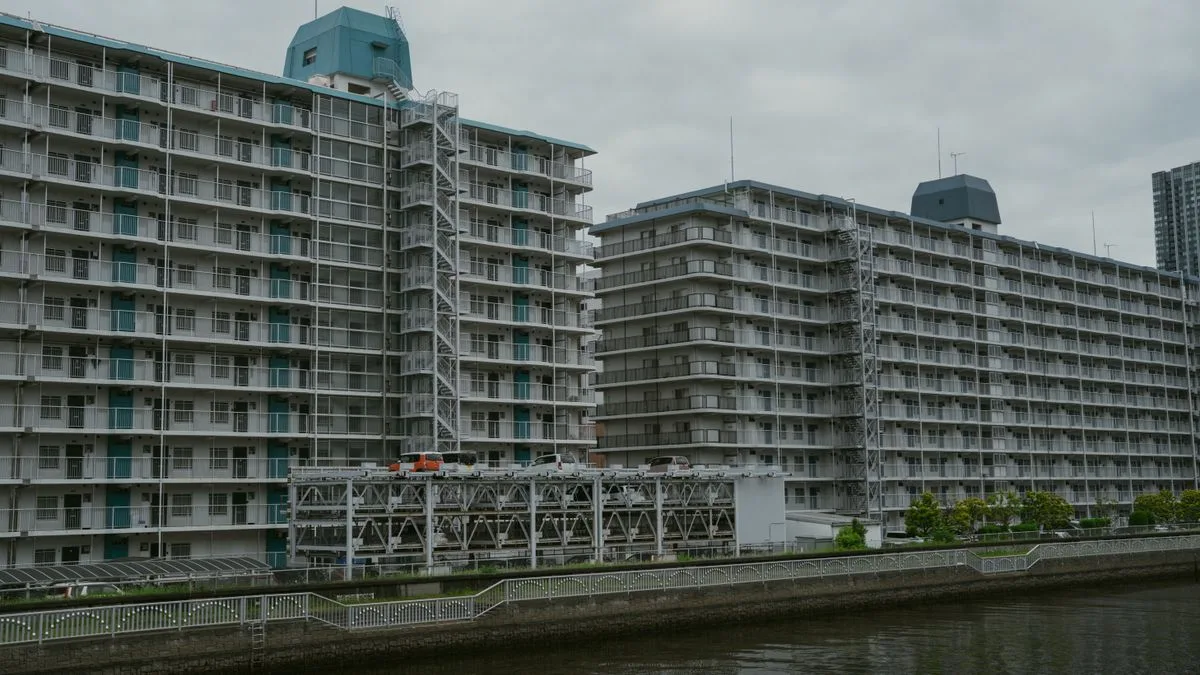 運河沿いに並ぶ大規模な集合住宅。バルコニーが規則正しく並び、手前に立体駐車場がある