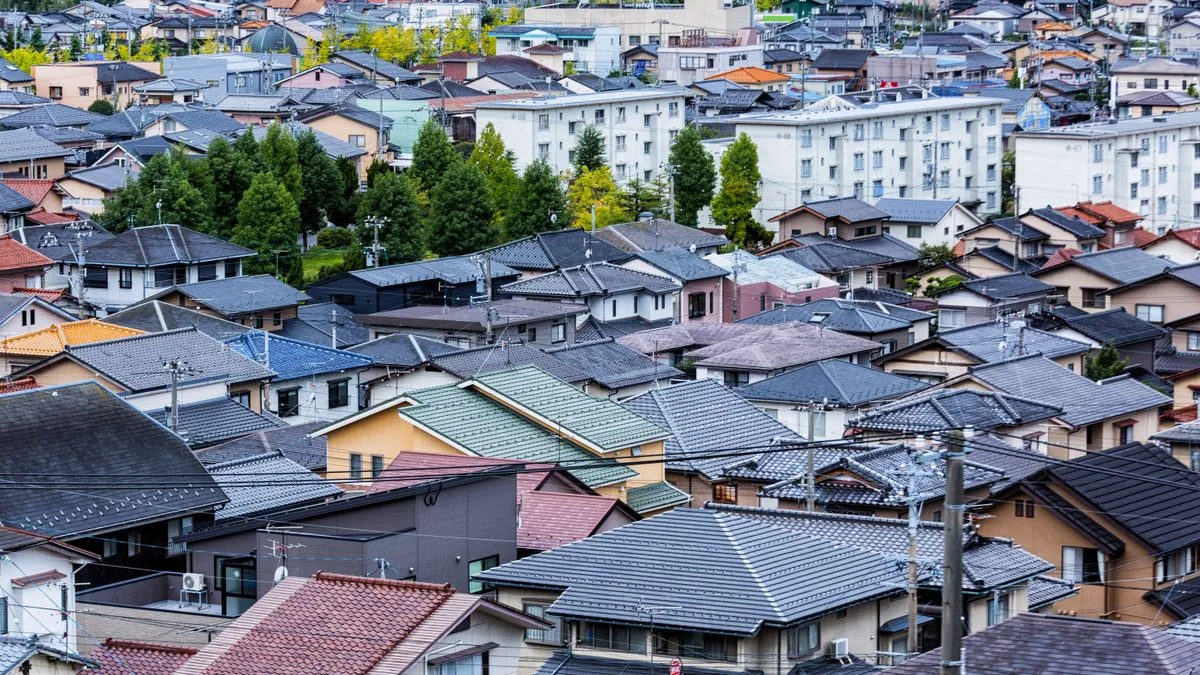 住宅地を見下ろした写真。戸建ての瓦屋根が並ぶ奥に、中層の集合住宅が建っている