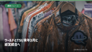 衣料品店のハンガーに並ぶ服のイメージ写真とワールド・TSI経営統合の見出し。両社の実店舗ではありません。