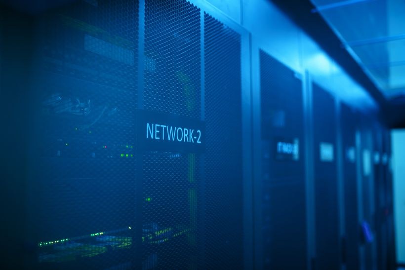 青い照明のサーバールームに並ぶネットワーク機器