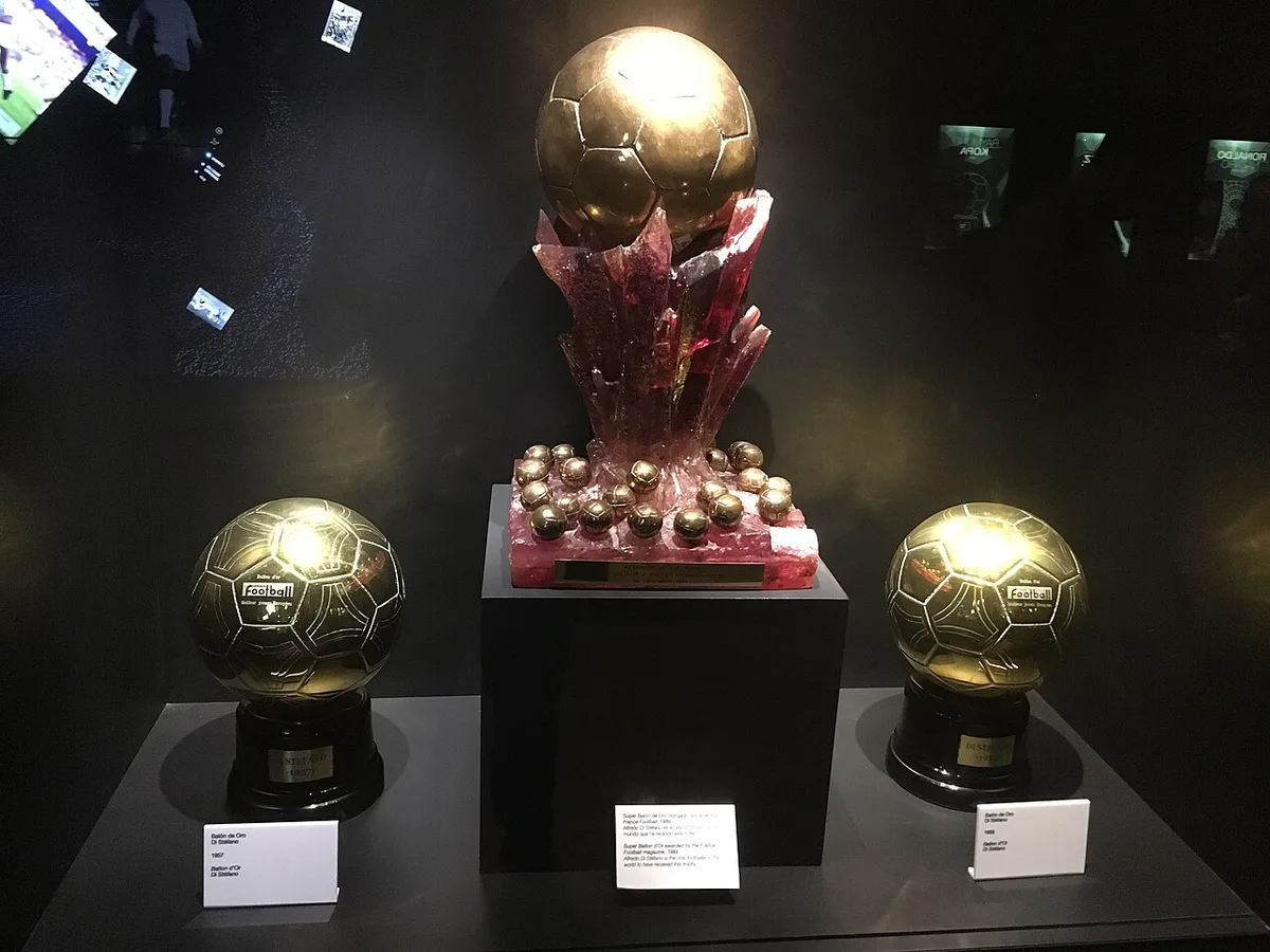 金色のサッカーボールの形をしたバロンドールのトロフィー2つと、赤い台座に金のボールがのったスーパー・バロンドール