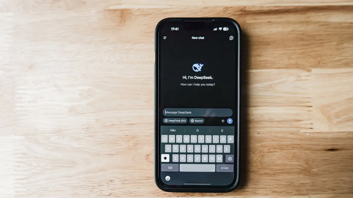 木の机に置かれたスマートフォン。画面にDeepSeekのチャットアプリの入力画面が表示されている