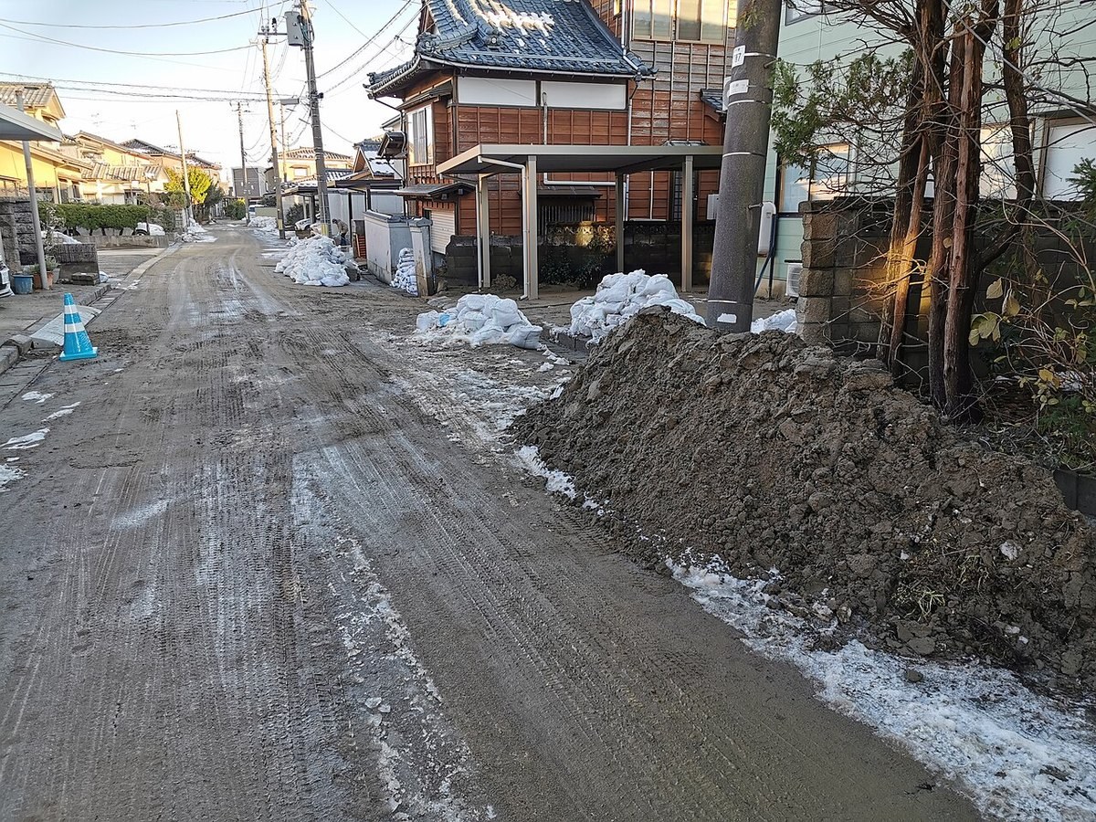 道路の脇に積み上げられた泥と砂の山と、土のう袋が並ぶ住宅街
