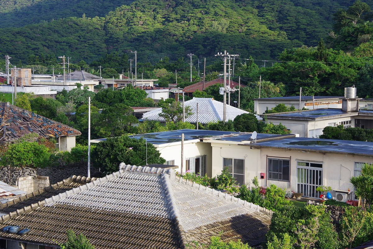 伊平屋島の我喜屋の集落。赤瓦や白い漆喰の屋根の家が並び、奥に緑の山が見える