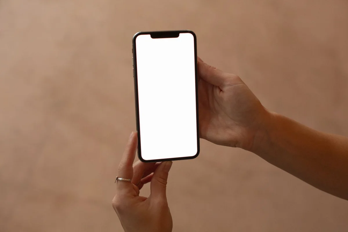 スマートフォンを両手で持つイメージ写真。JFAアプリの実画面ではない
