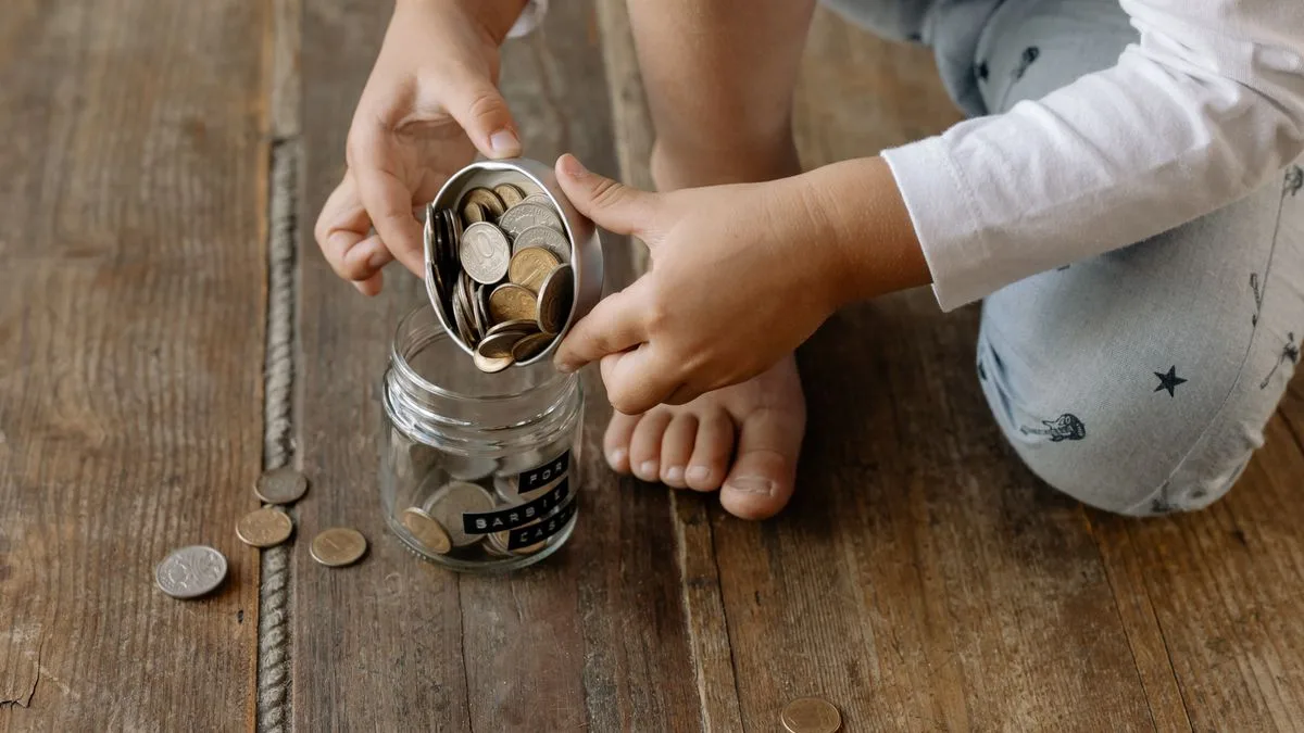 子どもがガラスの瓶に硬貨を入れている