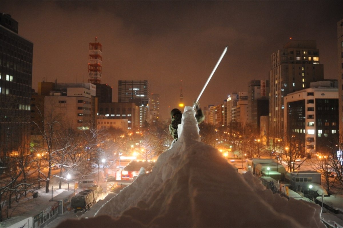 さっぽろ雪まつりの大雪像を夜間に作る陸上自衛隊員。雪の山の上から大通公園とテレビ塔の方向を望む