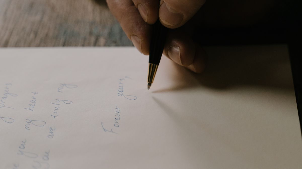 白い紙にペンで文字を書いている手元のアップ