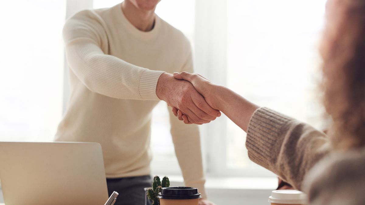 打ち合わせで握手をする人たち。法人化や契約条件を確認する場面のイメージ