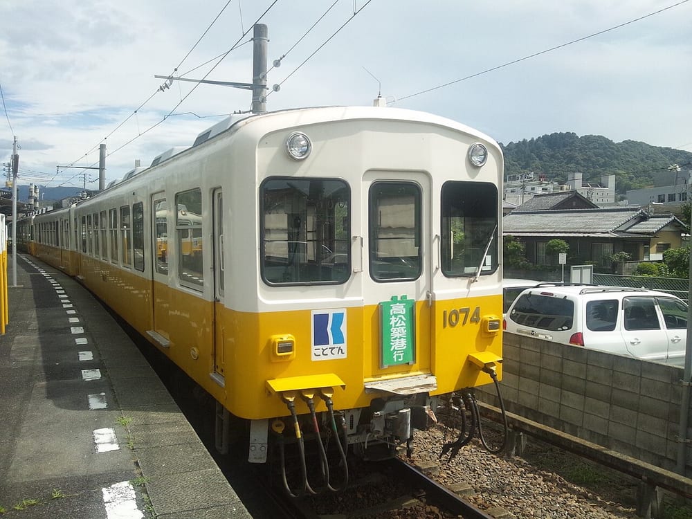 ことでん1070形の1074号。白とクリーム色の車体の下半分が黄色の電車で、前面に高松築港行きの表示