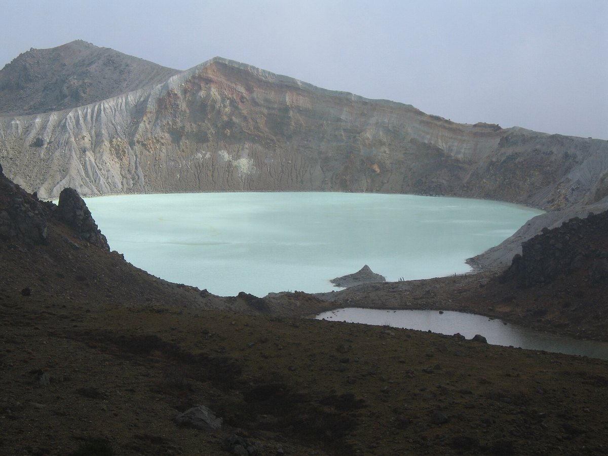 草津白根山の火口湖、湯釜。火口壁に囲まれた乳白色がかった緑色の湖