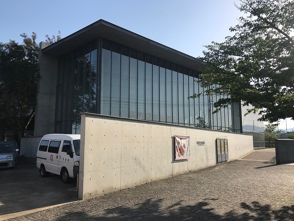 尾道市立美術館の外観。コンクリートの壁とガラス張りの建物が、千光寺公園の木々の間に建っている
