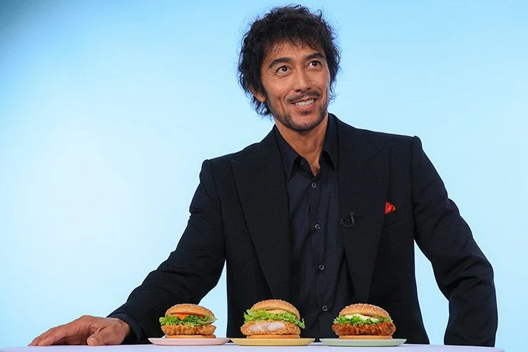 新しいチキンバーガー3種を前に座る阿部寛さん